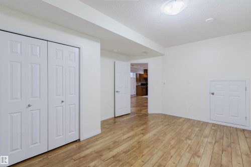 Hardwood flooring, white bi-fold closet doors, white paneled door, wall-mounted ceiling light fixture - 11608 96 Street Nw, Edmonton, AB 