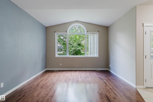 Vaulted ceiling with an arched transom window, wood-finish flooring, and a paneled entry door with frosted glass - 11608 96 Street Nw, Edmonton, AB 