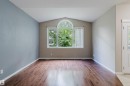 Vaulted ceiling with an arched transom window, wood-finish flooring, and a paneled entry door with frosted glass - 11608 96 Street Nw, Edmonton, AB 