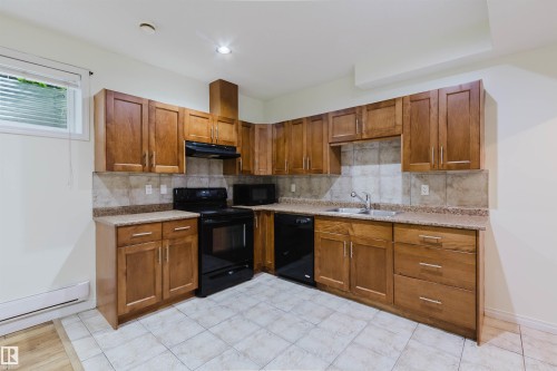 Wood-finish cabinetry with silver-tone hardware, speckled countertops, tile backsplash, and black appliances - 11608 96 Street Nw, Edmonton, AB 