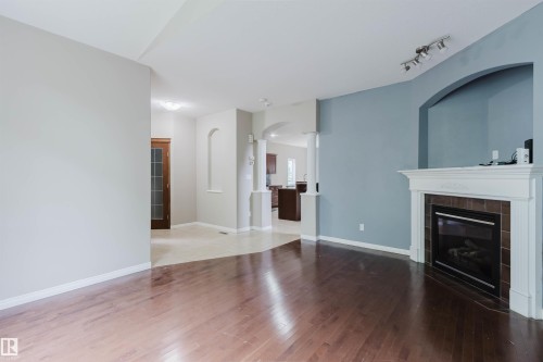 Hardwood-finish flooring, built-in fireplace with tile surround, arched alcove, track lighting, and a paneled wood door - 11608 96 Street Nw, Edmonton, AB 