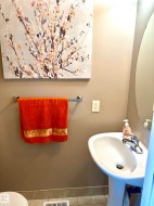 Pedestal sink with chrome faucet, wall-mounted mirror, and tile flooring - 