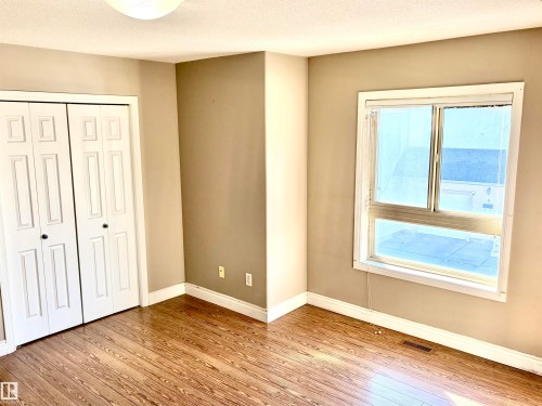Wood-finish flooring, neutral wall tones, white trim, and a window for natural illumination - #17 16317 64 St Nw, Edmonton, AB 