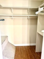 Built-in closet system featuring multiple shelves, hanging rods, and wood-finish flooring - 