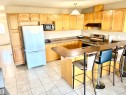 Kitchen featuring extensive light wood cabinetry, a tile backsplash, a built-in oven, a breakfast bar, and tile flooring - #17 16317 64 St Nw, Edmonton, AB 