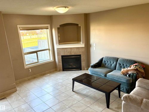Recessed electric fireplace with tiled surround, corner arch niche, and built-in mantle - #17 16317 64 St Nw, Edmonton, AB 