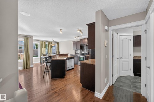 Expansive wood-finish flooring throughout, dark wood-finish cabinetry, stainless steel appliances, breakfast bar, and recessed lighting - 1850 Rutherford Road Sw, Edmonton, AB 