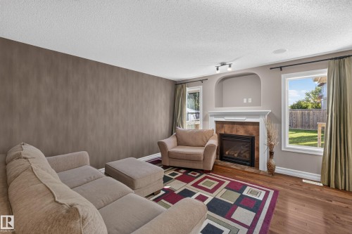 Hardwood-finish flooring, built-in fireplace with tile surround, white mantel, and arched alcove, and multiple windows - 1850 Rutherford Road Sw, Edmonton, AB 