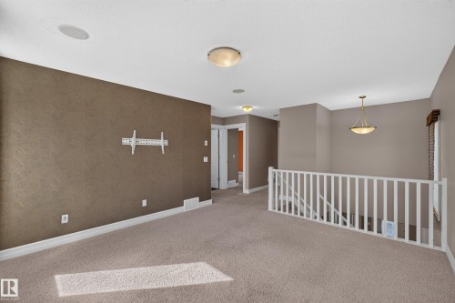 Carpeted open-concept space with a white railing, recessed lighting, and a mounted light fixture - 1850 Rutherford Road Sw, Edmonton, AB 