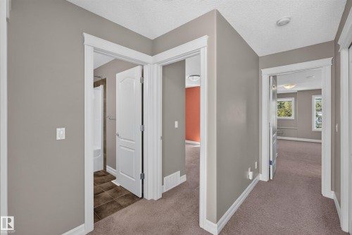 Hallway with neutral wall tones, white trim, and carpeting - 1850 Rutherford Road Sw, Edmonton, AB 