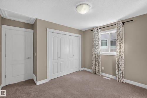 Neutral-toned walls with white trim, built-in bi-fold closet, single window, and flush mount ceiling light - 1850 Rutherford Road Sw, Edmonton, AB 
