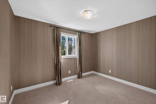 Neutral-toned striped wallpaper, flush-mount ceiling light fixture, and window with white trim - 1850 Rutherford Road Sw, Edmonton, AB 