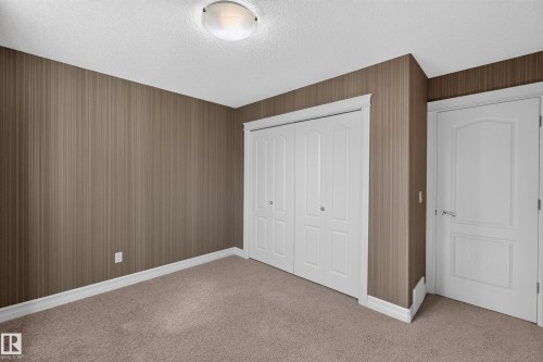 Carpeted flooring with white trim, a flush mount ceiling light, and white paneled doors - 1850 Rutherford Road Sw, Edmonton, AB 