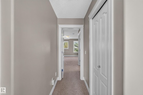 Hallway with neutral wall tones and carpeted flooring - 1850 Rutherford Road Sw, Edmonton, AB 