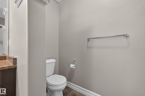 Vanity with a polished stone countertop, a white toilet, and a chrome towel bar - 1850 Rutherford Road Sw, Edmonton, AB 