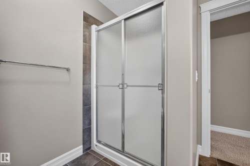 Shower enclosure with frosted glass panels and chrome framing, complemented by a tiled surround - 1850 Rutherford Road Sw, Edmonton, AB 