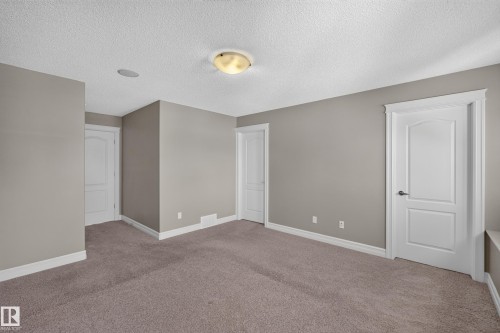 Neutral-toned walls, plush carpeting, white trim, arch-top panel doors, and a ceiling-mounted light fixture - 1850 Rutherford Road Sw, Edmonton, AB 