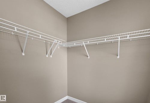 Corner closet with white wire shelving and hanging rods - 1850 Rutherford Road Sw, Edmonton, AB 
