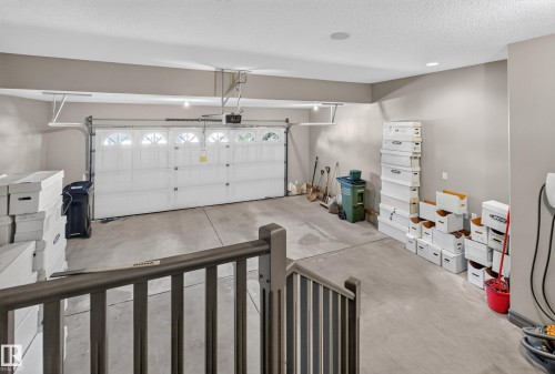 Garage featuring a concrete floor, painted walls, and a white overhead door with upper window inserts - 1850 Rutherford Road Sw, Edmonton, AB 