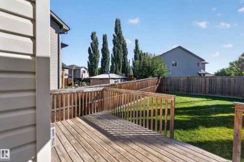 Wood deck with a railing and steps, leading to a fenced backyard featuring a manicured lawn - 1850 Rutherford Road Sw, Edmonton, AB 