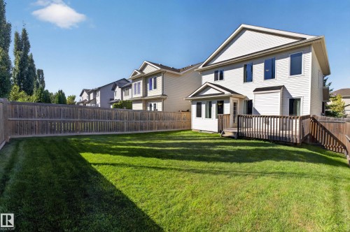Expansive lawn area with a full wood privacy fence, a multi-level wood deck, and a white siding exterior - 1850 Rutherford Road Sw, Edmonton, AB 