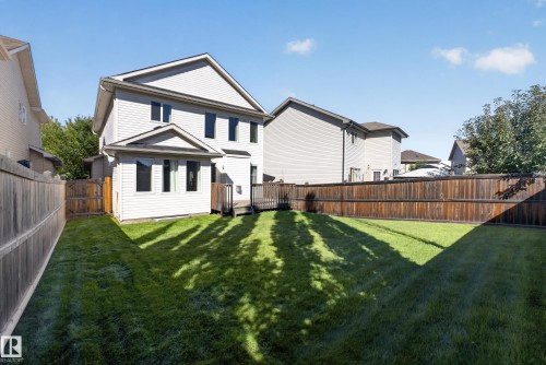 Expansive backyard featuring a manicured lawn, a full wood privacy fence, and an attached deck - 1850 Rutherford Road Sw, Edmonton, AB 