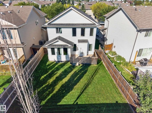 Expansive fenced backyard featuring a manicured lawn, wood deck, and a lower-level concrete patio - 1850 Rutherford Road Sw, Edmonton, AB 