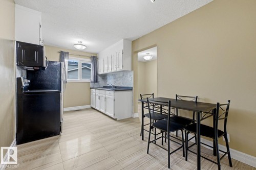Kitchen featuring white cabinetry, black appliances, a double basin sink, and tile flooring - 11317 22 Avenue Nw, Edmonton, AB 