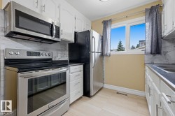 White cabinetry with brushed nickel hardware, light-toned tile flooring, stainless steel appliances, and a marble-finish backsplash - 