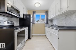Kitchen featuring white cabinetry, light-colored flooring, stainless steel appliances, and a window - 