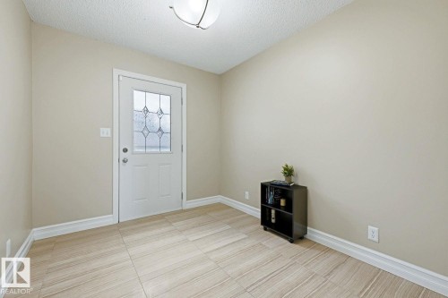 Entryway featuring a white door with decorative glass, light-colored tile flooring, and a flush-mount ceiling light - 11317 22 Avenue Nw, Edmonton, AB 