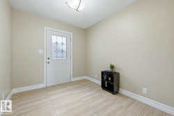 Entryway featuring a white door with decorative glass, light-colored tile flooring, and a flush-mount ceiling light - 