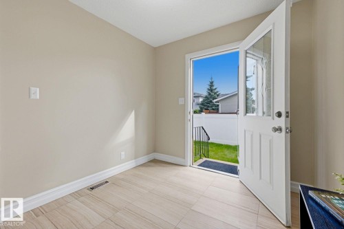 Light-toned tiled flooring throughout, neutral wall paint, and a glass-paneled entry door - 11317 22 Avenue Nw, Edmonton, AB 