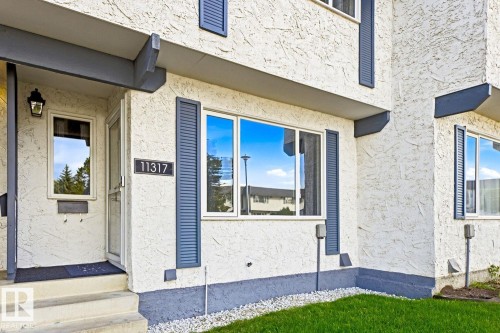 Stucco exterior with contrasting trim, permanent address numbering, and established landscaping - 11317 22 Avenue Nw, Edmonton, AB 