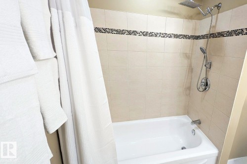 Bathtub with tiled surround featuring a decorative mosaic border - 11317 22 Avenue Nw, Edmonton, AB 