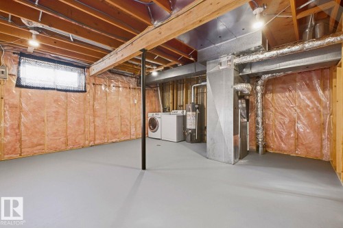 Utility space featuring exposed wood beams, a painted concrete floor, and a window with a security grate - 11317 22 Avenue Nw, Edmonton, AB 