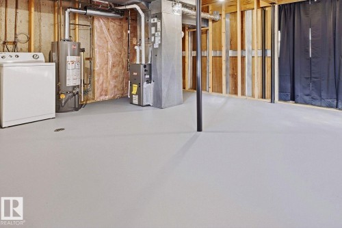 Unfinished basement with a painted concrete floor, exposed wood framing, and utility hookups - 11317 22 Avenue Nw, Edmonton, AB 