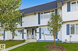 Stucco exterior with contrasting trim, multiple large windows, and a dark shingle roof - 