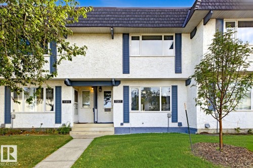 White stucco exterior with blue trim accents and dark shingle roofing - 11317 22 Avenue Nw, Edmonton, AB 