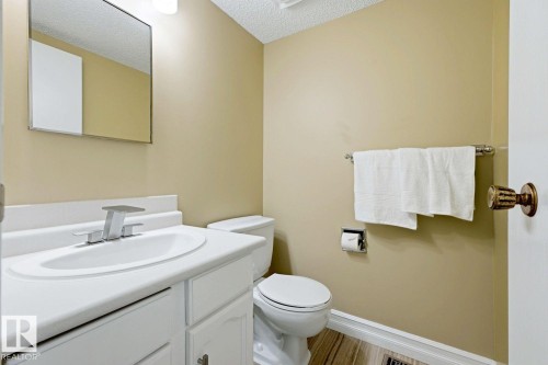 White vanity with a built-in sink, chrome fixtures, and a wall-mounted mirror - 11317 22 Avenue Nw, Edmonton, AB 