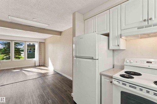 White kitchen cabinetry with a light-toned countertop, accompanied by a white refrigerator and range - 17351 85 Avenue Nw, Edmonton, AB 