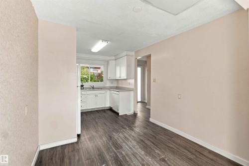 Kitchen featuring white cabinetry, a sink, and dark wood-finish flooring - 17351 85 Avenue Nw, Edmonton, AB 