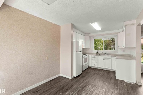 Kitchen featuring white cabinetry, light-toned countertops, white appliances, and wood-finish flooring - 17351 85 Avenue Nw, Edmonton, AB 