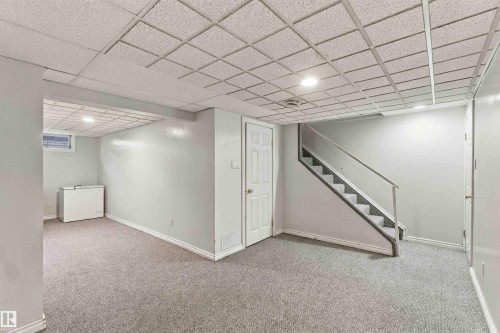 Carpeted flooring, drop ceiling with recessed lighting, painted walls, interior door, and staircase with railing - 17351 85 Avenue Nw, Edmonton, AB 