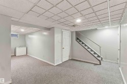 Carpeted flooring, drop ceiling with recessed lighting, painted walls, interior door, and staircase with railing - 