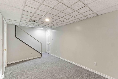 Finished lower level with carpet flooring, white walls, and a suspended grid ceiling - 17351 85 Avenue Nw, Edmonton, AB 
