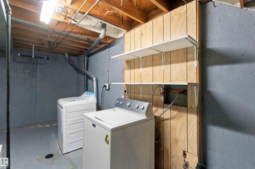 Laundry area featuring concrete walls, exposed wood ceiling joists, and built-in shelving - 17351 85 Avenue Nw, Edmonton, AB 