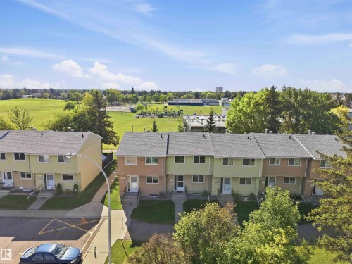 Townhome row with individual entryways, pitched roofs, and mature landscaping - 17351 85 Avenue Nw, Edmonton, AB 