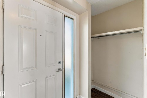 Entryway featuring a paneled door with a sidelight, a coat closet with an integrated hanging rod, and wood-finish flooring - 17351 85 Avenue Nw, Edmonton, AB 
