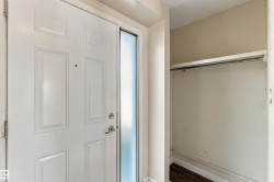 Entryway featuring a paneled door with a sidelight, a coat closet with an integrated hanging rod, and wood-finish flooring - 